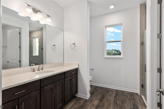 bathroom featuring a stall shower, baseboards, toilet, wood finished floors, and vanity