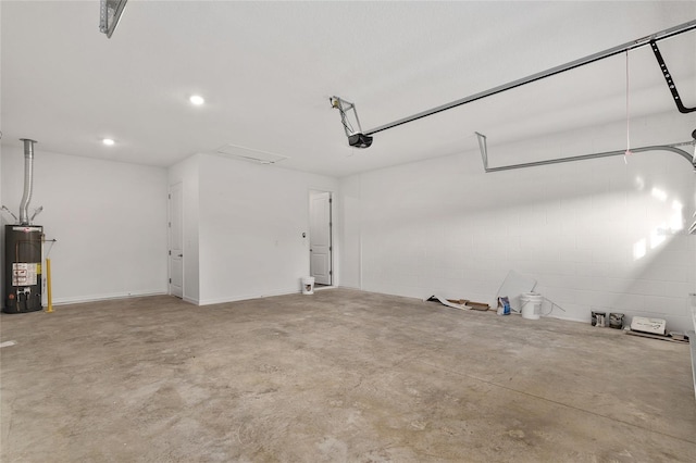 garage with a garage door opener, concrete block wall, and gas water heater