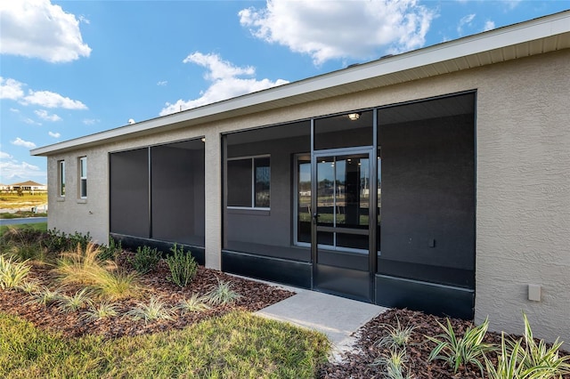 view of side of home featuring a sunroom and stucco siding