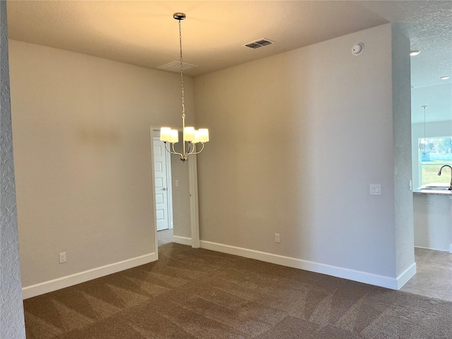 empty room with carpet floors, visible vents, baseboards, and an inviting chandelier