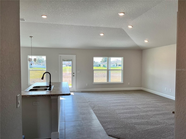 kitchen with carpet floors, a sink, a textured ceiling, and baseboards