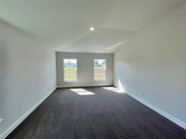 carpeted empty room featuring lofted ceiling and baseboards