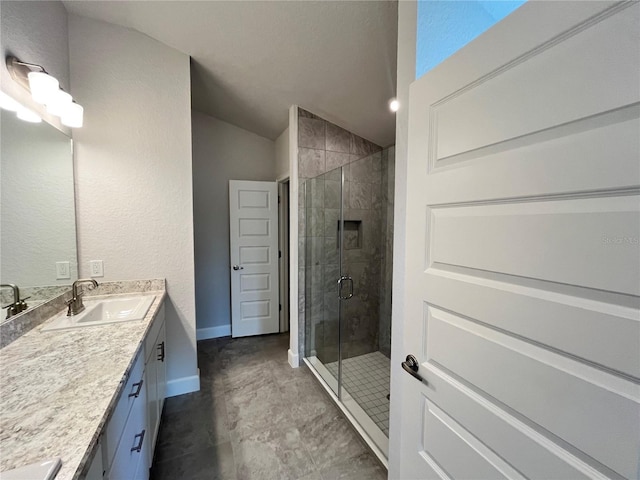 full bath featuring a shower stall, baseboards, vaulted ceiling, and vanity