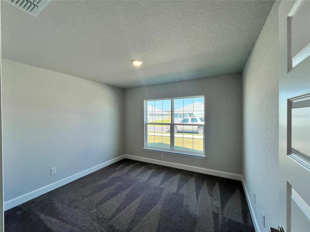 spare room featuring visible vents, a textured ceiling, dark carpet, and baseboards