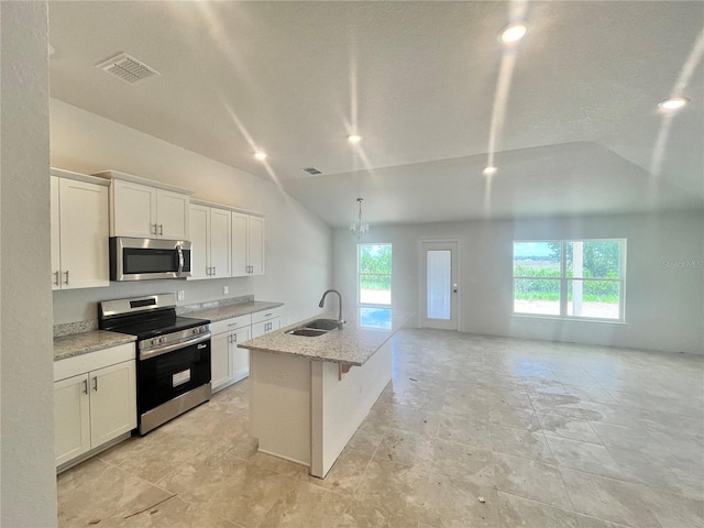 4381 SW 90th Pl, Ocala, FL 34476 - kitchen featuring appliances with stainless steel finishes, lofted ceiling, white cabinetry, light stone countertops, and an island with sink