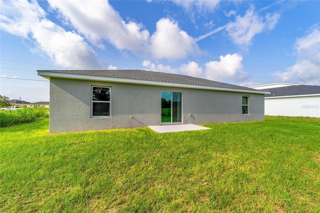 back of house featuring stucco siding, a patio, and a yard