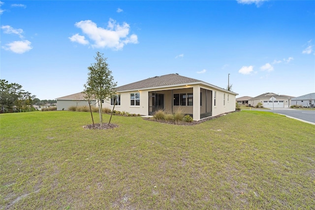 rear view of property featuring a yard and stucco siding