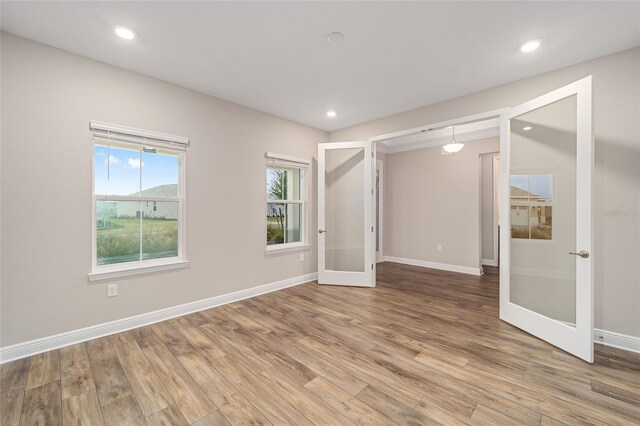 spare room with baseboards, french doors, and light wood-style floors