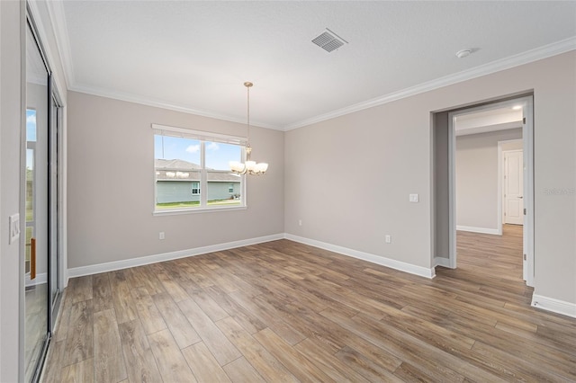 empty room featuring crown molding, visible vents, a notable chandelier, and wood finished floors