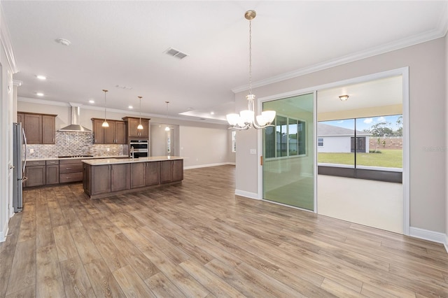 kitchen with tasteful backsplash, open floor plan, stainless steel appliances, light countertops, and wall chimney range hood