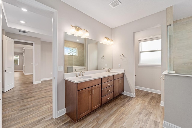 full bath with a healthy amount of sunlight, visible vents, a sink, and wood finished floors