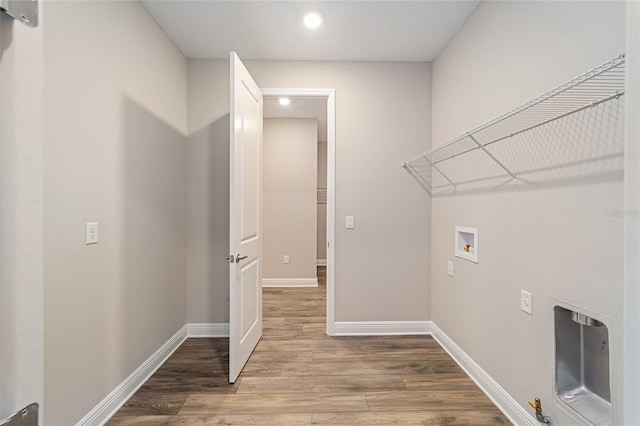 clothes washing area featuring laundry area, baseboards, washer hookup, and light wood finished floors