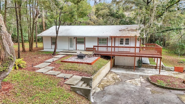 ranch-style house featuring driveway, an outdoor fire pit, metal roof, and a carport