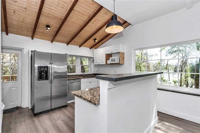 kitchen featuring light wood finished floors, hanging light fixtures, appliances with stainless steel finishes, white cabinetry, and a sink