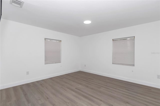 unfurnished room featuring visible vents, baseboards, and dark wood-style flooring