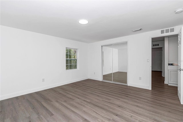 unfurnished bedroom with dark wood-style floors, visible vents, and baseboards