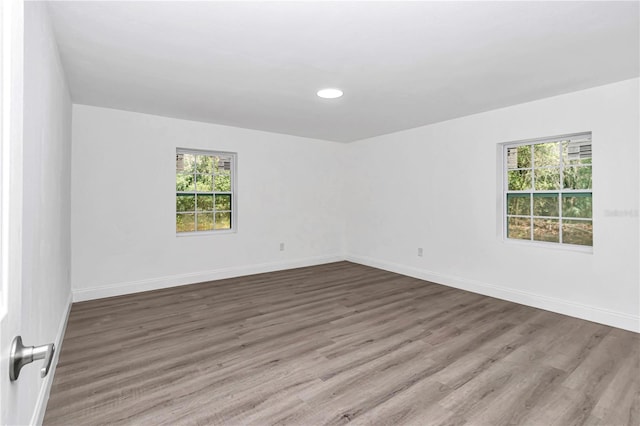 spare room with recessed lighting, baseboards, and wood finished floors