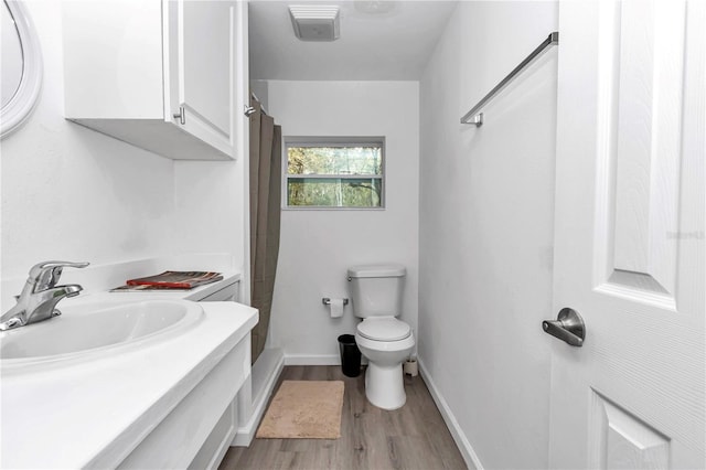 bathroom featuring curtained shower, toilet, vanity, wood finished floors, and baseboards