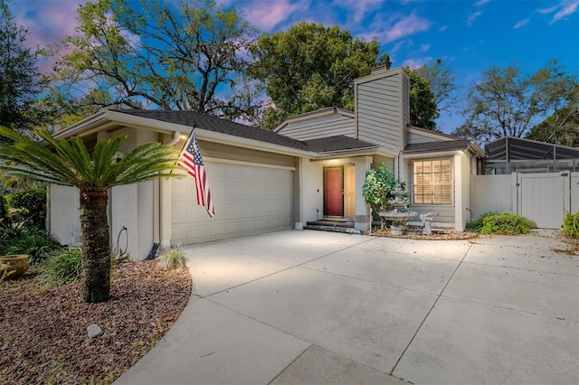 view of front facade featuring stucco siding, an attached garage, driveway, and a gate