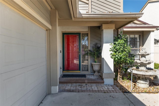 view of exterior entry with an attached garage and stucco siding