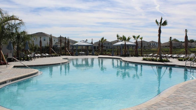 community pool with a gazebo, a patio area, fence, and a residential view