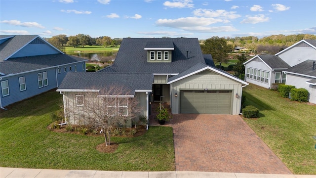 view of front of house featuring a shingled roof, decorative driveway, an attached garage, and a front yard