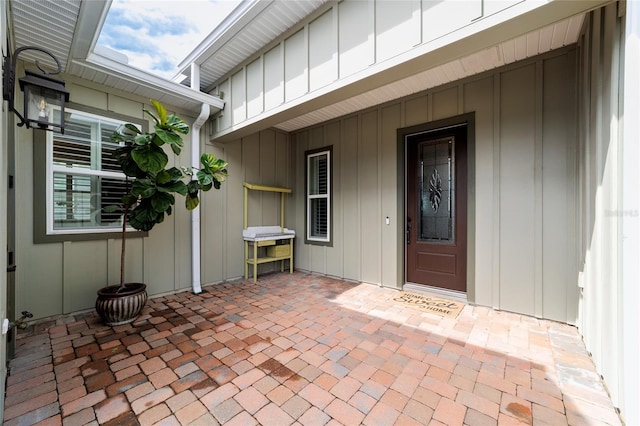 entrance to property with board and batten siding and a patio area