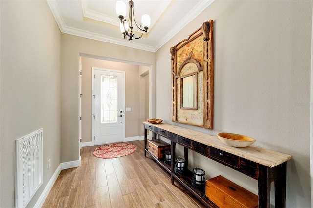 entryway with a notable chandelier, visible vents, baseboards, light wood finished floors, and crown molding