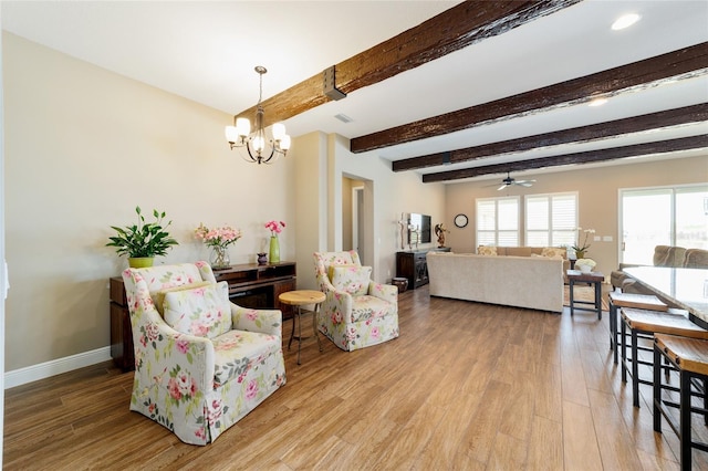 living room featuring ceiling fan with notable chandelier, wood finished floors, beam ceiling, and baseboards