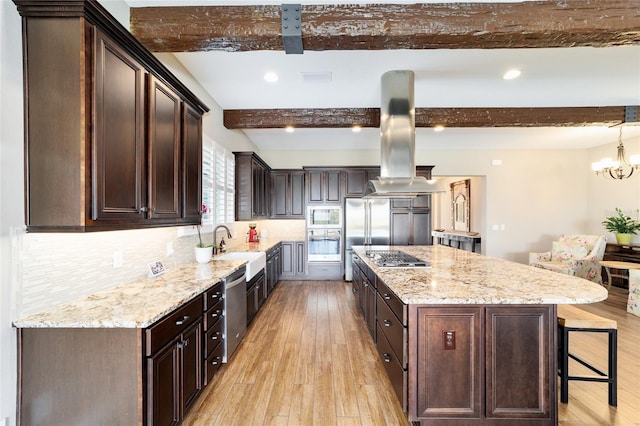 kitchen featuring built in appliances, dark brown cabinets, light wood finished floors, and a kitchen bar