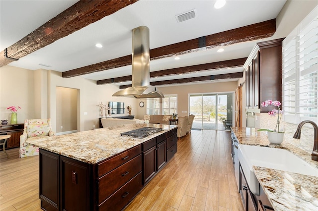 kitchen featuring light wood-style floors, stainless steel gas cooktop, open floor plan, and a sink