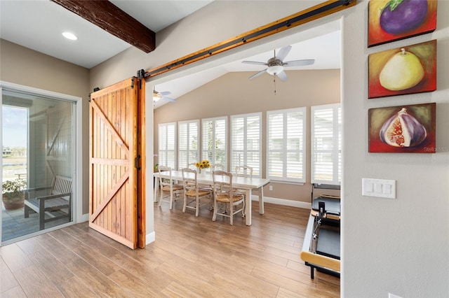 interior space with a ceiling fan, wood finished floors, lofted ceiling with beams, and a barn door