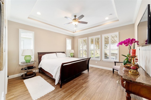 bedroom with light wood-type flooring, baseboards, a raised ceiling, and crown molding