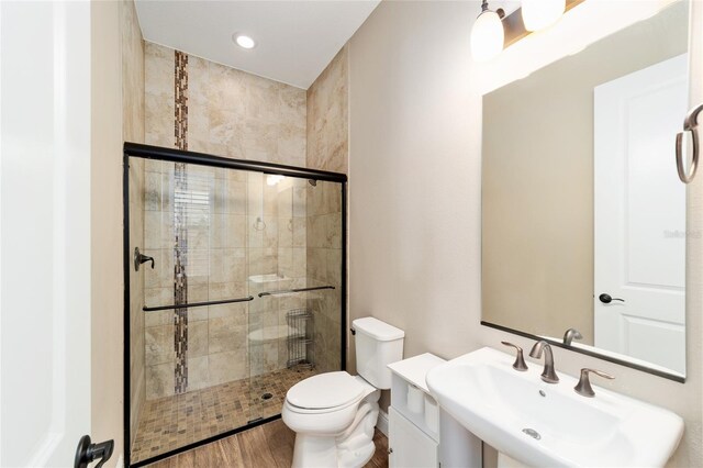 full bath featuring a sink, wood finished floors, a shower stall, and toilet