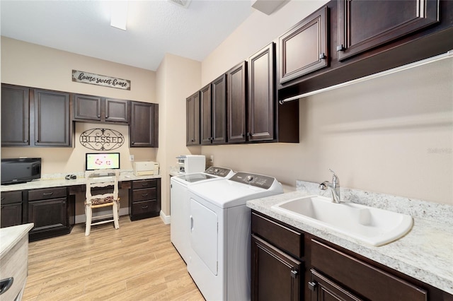 clothes washing area featuring light wood finished floors, independent washer and dryer, a sink, and cabinet space