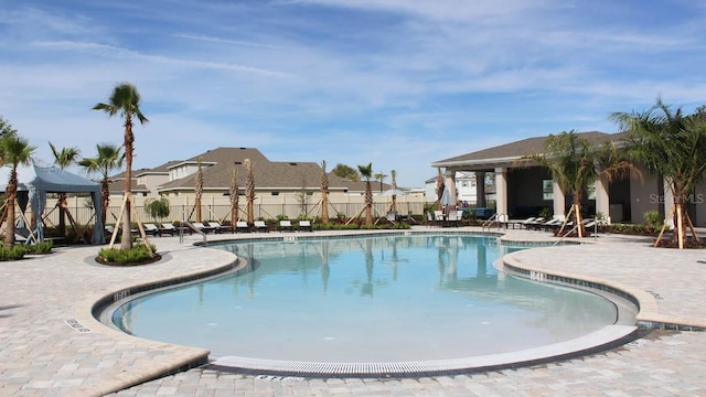 community pool featuring a patio area, a residential view, and fence