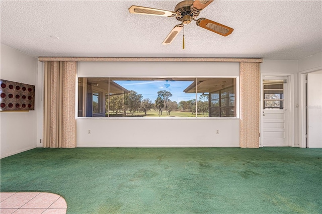 carpeted spare room with a textured ceiling, ceiling fan, and a healthy amount of sunlight