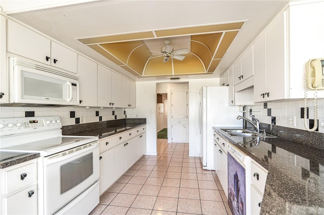 kitchen with white appliances, a tray ceiling, white cabinets, and a sink