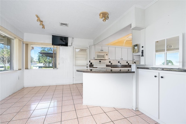 kitchen featuring dark countertops, light tile patterned flooring, range, and white microwave