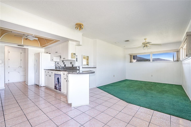 kitchen with dark countertops, light colored carpet, freestanding refrigerator, ceiling fan, and a textured ceiling