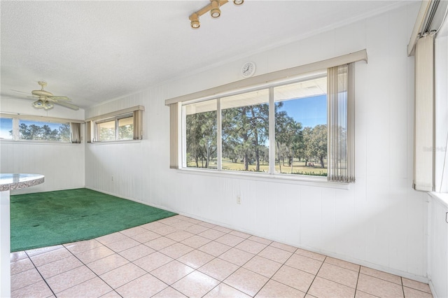 empty room featuring light carpet, light tile patterned flooring, ceiling fan, and a textured ceiling