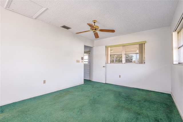 carpeted spare room with visible vents, attic access, ceiling fan, a textured ceiling, and baseboards