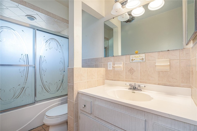 bathroom with tile walls, toilet, enclosed tub / shower combo, vanity, and tile patterned flooring