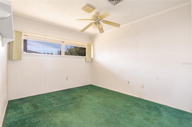 empty room featuring a textured ceiling, ceiling fan, carpet flooring, visible vents, and crown molding