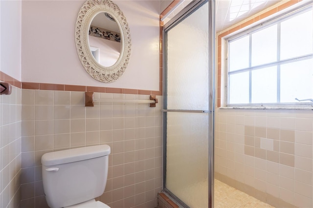 full bathroom featuring a wainscoted wall, a shower with door, tile walls, and toilet