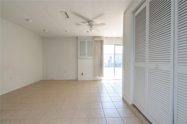 unfurnished room with ceiling fan, light tile patterned floors, a textured ceiling, and visible vents