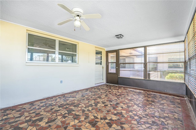 unfurnished sunroom featuring a ceiling fan and a healthy amount of sunlight