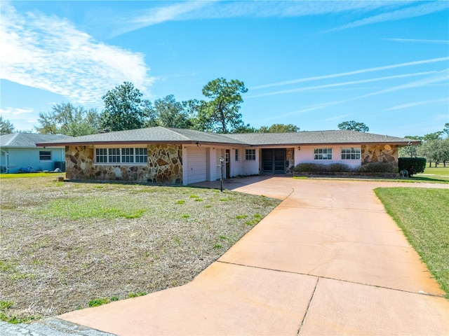 single story home featuring a garage, driveway, a front lawn, and stone siding