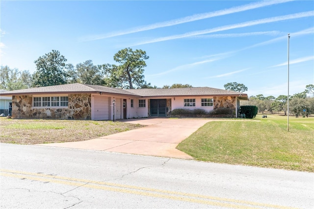 single story home featuring an attached garage, stone siding, a front lawn, and concrete driveway