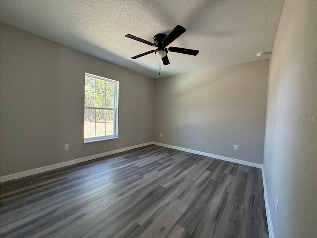 empty room with dark wood finished floors, a textured ceiling, baseboards, and ceiling fan